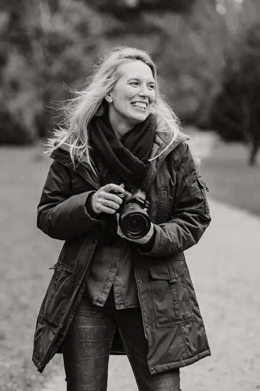 Black and white photo of Chantel holding a camera and smiling